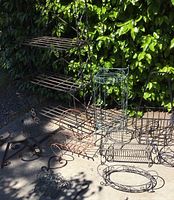 Photo showing the full lot arranged outdoors by greenery, including the metal baker's rack and assorted metal plant stands and hanging planter holders.