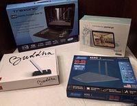 Photo showing all four boxed items together: Buddha Board, Trexonic portable DVD TV, Facebook Portal Go, Antop Aero+ indoor HDTV antenna