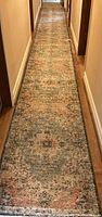 Full length of one long runner rug on hardwood floor in hallway.