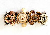 Top-down view of the signed AYALA BAR bracelet highlighting the twisted rope-like details and circular center elements with rhinestones.