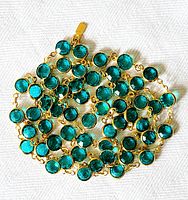 Close-up of linked turquoise faceted crystals set in gold-tone metal showing the sparkle and bezel settings.