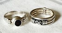 Photo showing both rings side by side including garnet ring and triple band swirl design ring
