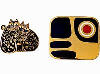 Image showing both brooches side by side. Left brooch depicts two stylized Calico cats in dark blue and gold tone enamel. Right brooch is abstract with dark blue and gold tones and a red-orange circle.