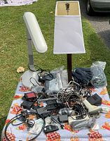 Wide view of all items on table including two desk lamps, leather gloves in bags, and miscellaneous electrical components