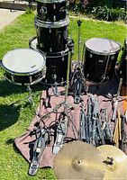 Photo of drums, cymbals, hardware, and sticks laid out on outdoor surface