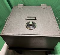 Top view of vintage large metal safe with combination dial on top and black handle near dial