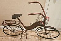 Full view of the metal bicycle showing frame, seat, handlebars, basket, and wheels.