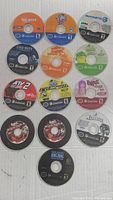 Photo showing 14 loose Nintendo GameCube discs arranged on a white surface, no cases included. Various game titles visible with original disc labels and artwork.