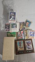 Full lot of assorted vintage baseball cards spread on floor including a wooden plaque with two cards.