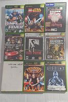 Photo showing 8 Original Xbox game cases with cover art for NFL Fever 2003, LEGO Star Wars, Shadow Ops, Midnight Club II, Max Payne, Ghost Recon, NASCAR Heat 2002 (case only), Monster Garage, and Riddick.