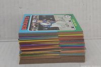 Stack of vintage baseball cards with Braves card showing on top, showing thickness and variety of colors of card backings.