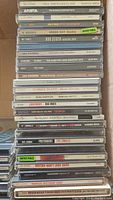 Stack of vintage rock CDs showing titles such as Paul Simon Graceland, Green Day Dookie, Bob Seger, Cars, Cure, Robert Plant, and others.