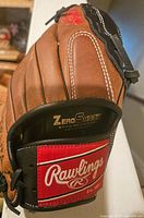 Close-up of the wrist strap showing Rawlings logo patch and Zero Shock labeling on the glove palm.