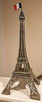 Full view of vintage Eiffel Tower metal statue showing detailed lattice design and flag at top.