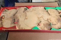 Top view of the entire hockey game table showing heavy water stains and discoloration on the playing surface with red and green painted paddles on metal rods.