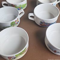 Top view close-up of six matching Campbell Soup bowls with colorful outdoor and children activity scenes on the sides.