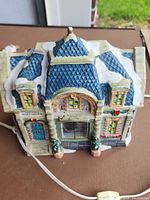 Front view of ceramic Christmas village building with blue roof, snow, and potted trees showing 'Post Office' sign on door.