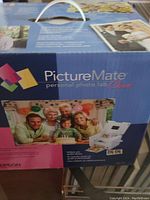 Front side of Epson PictureMate Personal Photo Lab Charm printer box showing product name and sample photo print images