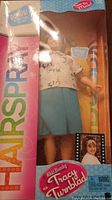 Front view of the sealed Hairspray Tracy Turnblad doll inside the original packaging showing doll wearing blouse and blue skirt with bonus label on the box.