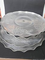 Stack of four vintage metal Lazy Susans with embossed floral design on tops and scalloped edges.