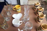 Overview of all mugs, glasses, steins, and dish on table, showing variety