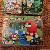 Top view showing three unopened Minecraft LEGO sets with pixelated blocky designs, including a large sheep figure and a Creeper character.