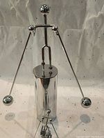 Large metal skiing figure with extended poles and skis standing on cylindrical base.