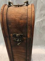 Side view of the vintage wooden wine case showing curved top, metal latch and wood grain texture