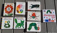 Top-down view of all nine Eric Carle board books arranged on a wooden floor, showing colorful covers and titles.