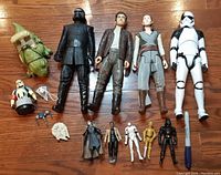 Collection of assorted Star Wars figures in various sizes laid on floor including 11-inch figures and smaller Galactic Heroes figures.