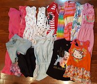 Assorted girl clothing size 5-6 laid out on floor showing various dresses, tops and shorts in colorful patterns and styles.