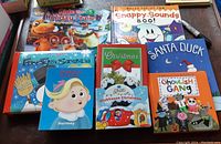 Eight children's holiday-themed books arranged flat on a surface including titles with dinosaurs, snowmen, and ghosts.