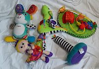 Group photo showing four main plush and fabric Lamaze baby toys including a rabbit, seahorse with piano keys, butterfly doll, and purple baby doll on white background.