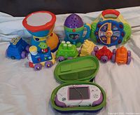 All toys displayed together including Leapster Explorer handheld device with case and assorted toddler toys