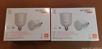 Two unopened Sengled Pulse LED wireless speaker bulb packages, each with 2 bulbs, featuring JBL speakers and 55W LED lighting.