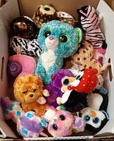 Photo of assorted Ty Beanie Boos stuffed animals in a box showing various characters and colors.