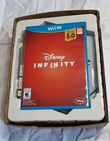 Photo showing the game case on top of the Disney Infinity base inside the original packaging box.