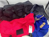 Photo showing four duffle bags in different colors and styles stacked together