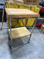 Side view of butcher block cart showing wooden top with juice groove and metal frame on wheels