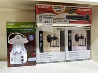 Magnavox digital TV converter box, Northpoint multifunction radio lantern, and two boxed Portfolio outdoor wall lanterns shown together.