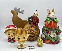 Overview of all vintage holiday collectible items in the lot showing figural planters, orange ceramic figure with elf, ceramic rabbit with carrots, wooden reindeer, and painted egg.