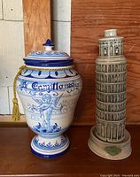 Front view of the ceramic biscotti jar and Leaning Tower of Pisa decanter side by side on wood surface.