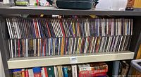 Two rows of various music CDs on a shelf showing a range of artists and titles including Rod Stewart and others