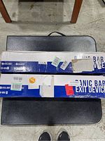 Two FH-950 B Fortstrong panic bar exit devices in original packaging laid flat on a black surface, showing the blue and white branded boxes with original labels.