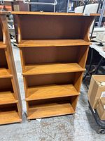 Front view of the wooden shelf showing four tiers with curved vertical sides.