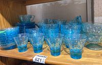 Wide view of all blue dimple glassware including glasses, bowls and tea cups.