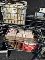 Metal shelf with two baskets and one wooden crate filled with various ceramic tiles of different colors and sizes.