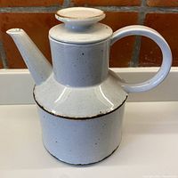 Front view of the Midwinter coffee pot showing the cream color with cinnamon speckles, tall spout, circular handle and flat lid top.