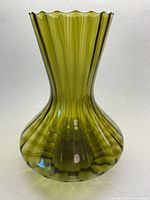 Front/profile view of olive green blown glass vase showing ribbed linear texture and flared scalloped rim.