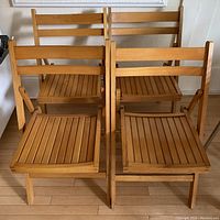Four vintage solid wood folding chairs arranged in two rows showing front view including seats and backs.